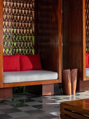 Gemütliche Sitzecke mit Holzwänden und roten Kissen in tropischem Ambiente