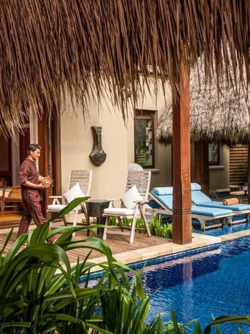 Villa mit privatem Pool und Loungestühlen in tropischem Garten