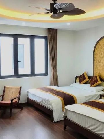 Gemütliches Zimmer mit zwei Betten, Holzstuhl und dekorativer Beleuchtung