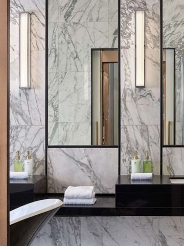 Luxuriöses Bad mit Marmorverkleidung und beleuchtetem Spiegel