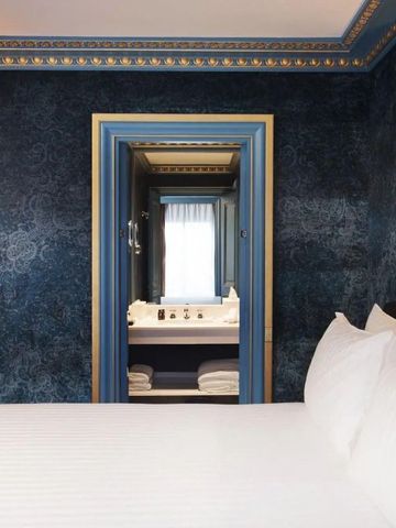 Opulentes Hotelzimmer mit blauen Wänden und Blick ins Badezimmer