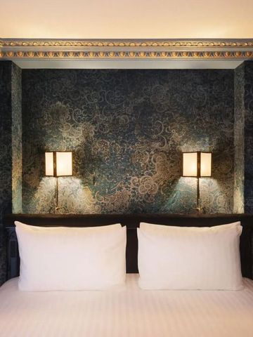 Gemütliches Bett mit stilvoller Wandverzierung und Lampen