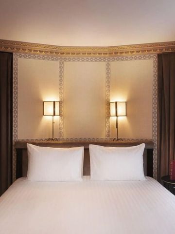 Elegantes Hotelzimmer mit zwei Wandlampen und luxuriösem Bett