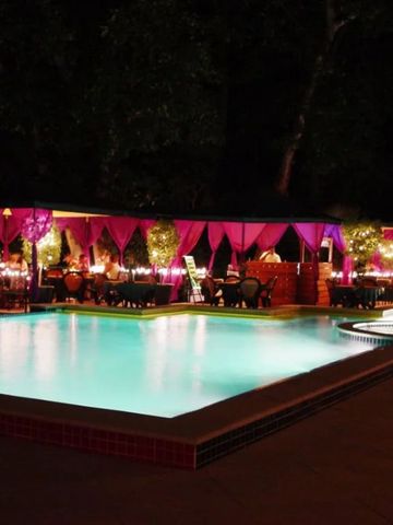 Beleuchteter Außenpool mit stilvoll dekorierten Sitzbereichen bei Nacht