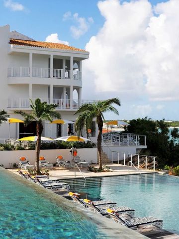 Pool mit Blick auf mehrstöckige Villa und Meer im Hintergrund