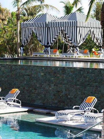 Streifenpavillon und Liegen am Pool