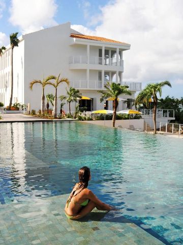 Gäste entspannen am Pool mit Blick auf Villa und Meer