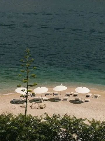 Privatstrand mit Liegen und Sonnenschirmen an türkisfarbenem Meer