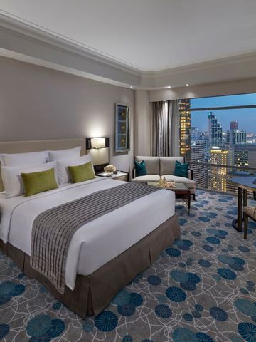 Komfortables Zimmer mit Kingsize-Bett und atemberaubendem Blick auf die nächtliche Skyline