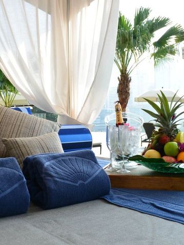 Luxuriöser Poolbereich mit Liegen und Obstarrangement unter Palmen