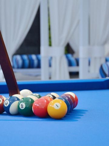 Billardtisch mit bunten Bällen und Liegen im Hintergrund