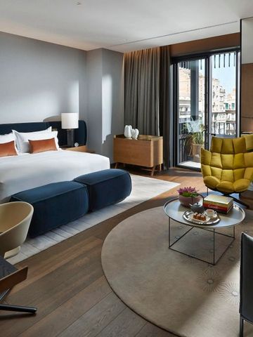 Modernes Hotelzimmer mit großem Bett, Sesseln und stilvollen Möbeln.