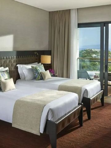 Modernes Hotelzimmer mit zwei Einzelbetten und großem Fenster mit Blick auf die Bucht