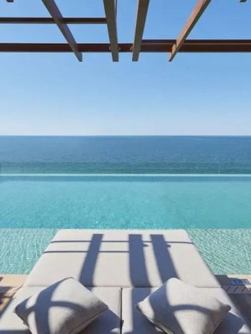 Infinity Pool mit Meerblick und Liegestühlen bei klarem Himmel