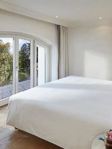 Helles Schlafzimmer mit großem Fenster und Blick auf den Garten