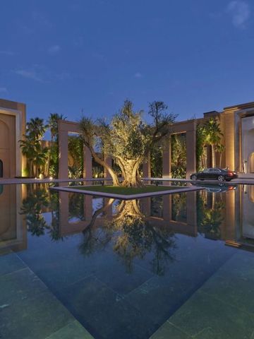 Abendaufnahme des Hotels mit reflektierendem Pool und Olivenbaum