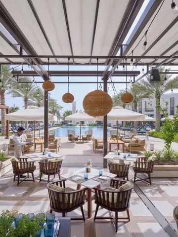 Gemütliche Terrasse mit Blick auf Pool und Palmen bei Sonnenschein