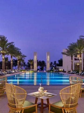 Beleuchteter Hotelpool bei Dämmerung mit umgebenden Palmen