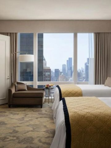 Helles Hotelzimmer mit zwei Betten und atemberaubender Aussicht auf die Skyline von New York