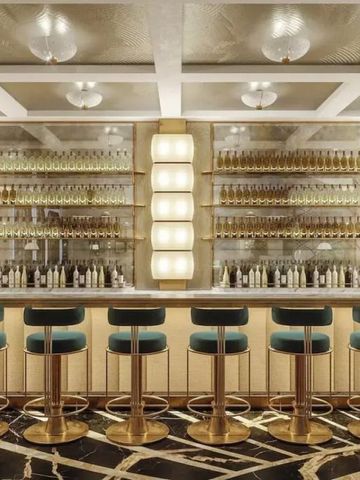 Elegant gestaltete Hotelbar mit goldenen Akzenten und Barhockern