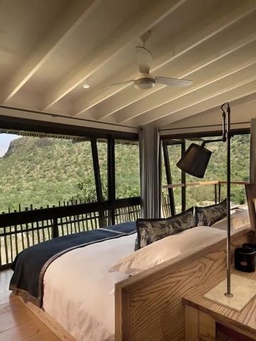 Schlafzimmer mit großen Fenstern und Ausblick auf die Natur