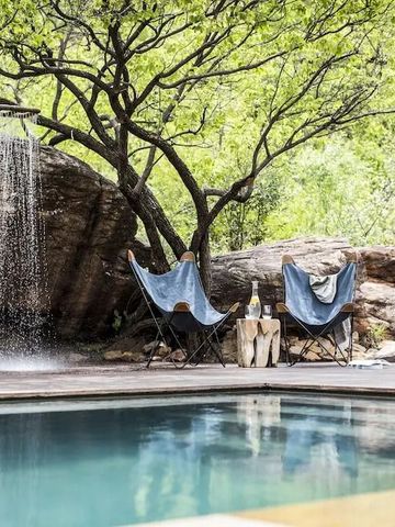 Poolbereich mit Wasserfall und entspannenden Liegen inmitten der Natur
