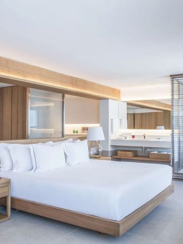 Lichtdurchflutetes Zimmer mit luxuriösem Bett und moderner Einrichtung