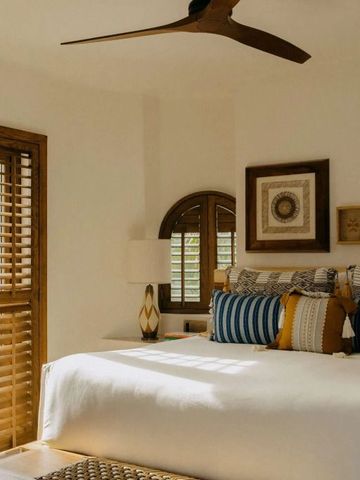 Helles Schlafzimmer mit großem Bett, Holzakzenten und Deckenventilator