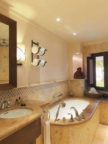 Luxuriöses Badezimmer mit Badewanne aus Naturstein und großem Spiegel