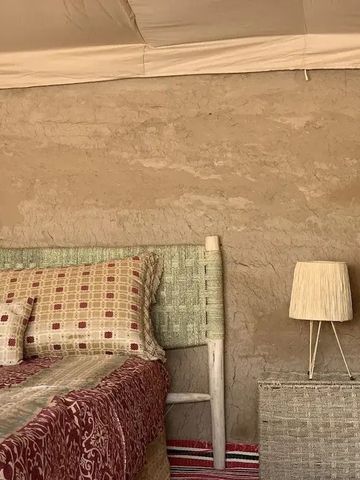 Detailansicht eines rustikalen Betts mit gemusterten Kissen und Lampe