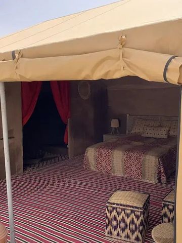 Zeltzimmer im Wüstencamp mit Teppichen und Holzstühlen