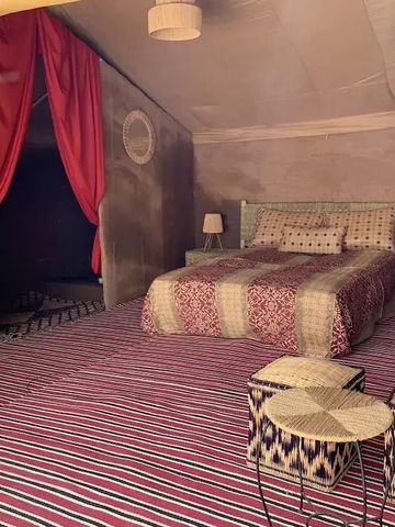 Geräumiges Zelt mit gemütlicher Bettwäsche und leuchtend-roten Vorhängen