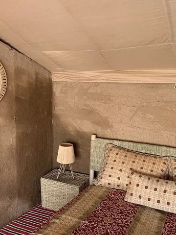 Einladendes Schlafzimmer im Zelt mit warmen Farben und weichen Textilien im Inara Camp