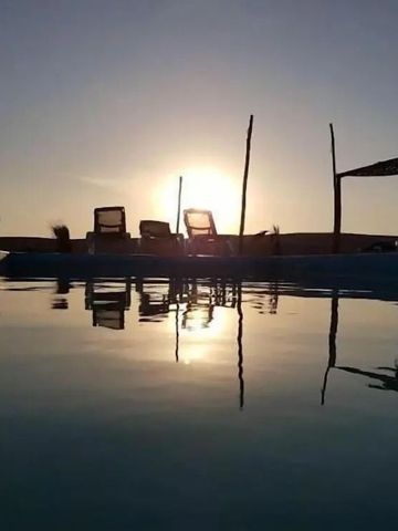 Pool im Inara Camp bei Sonnenuntergang mit Blick auf Liegestühle und Wüstenhimmel