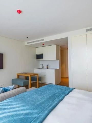 Modernes Hotelzimmer mit komfortablem Bett und kleiner Küchenzeile.