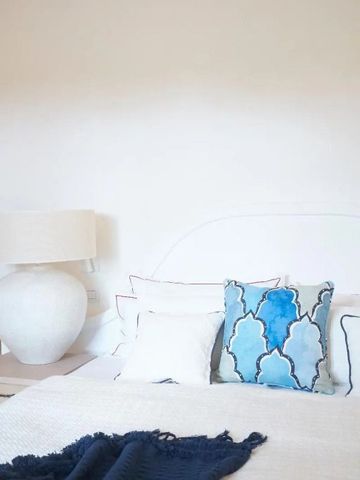 Luxuriöses Bett mit blauen und weißen Kissen in einem hellen Raum.