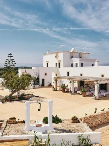 Weißes Gebäude mit mehreren Ebenen und Innenhof unter blauem Himmel.