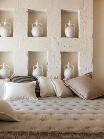 Gemütliche Sitzecke in einem Zimmer mit Kissen und dekorativen Vasen in der Wand.