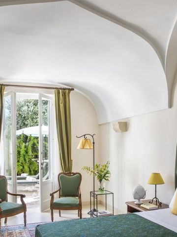 Elegantes Zimmer mit gewölbter Decke und Blick auf den grünen Innenhof durch große Fenster