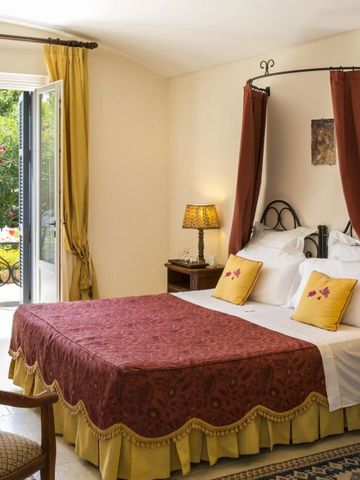 Elegantes Hotelzimmer mit Himmelbett und Terrasse mit Gartenblick