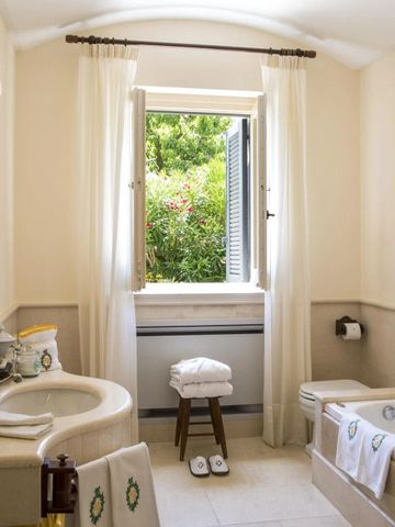 Luxuriöses Badezimmer mit Fensterblick auf grünen Garten