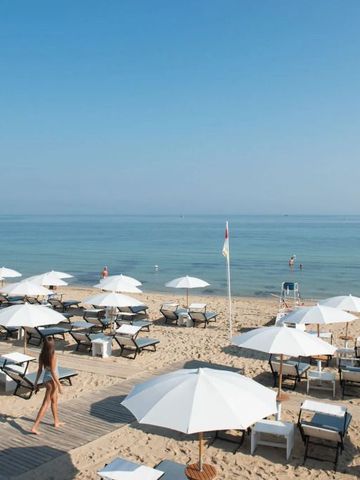 Sonnenschirme und Liegestühle an einem Strand mit Meerblick bei blauem Himmel