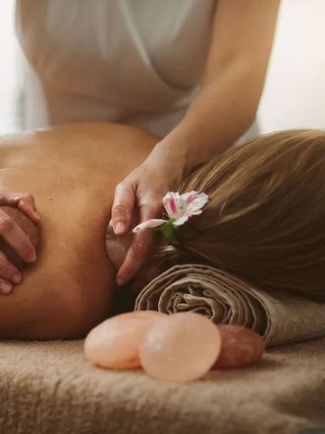 Frau genießt entspannende Massage im Spa mit Salzsteinen