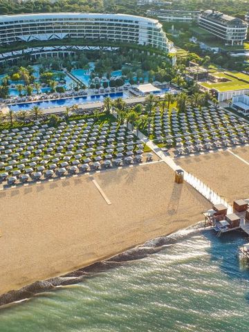 Strandbereich des Maxx Royal Belek mit Reihen von Sonnenschirmen und Liegen