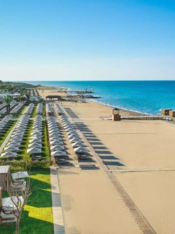 Breiter Sandstrand mit Reihen von Sonnenliegen und kristallklarem Meer