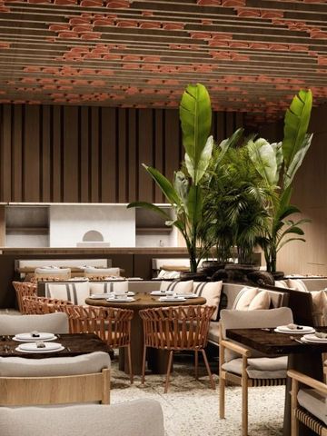 Elegantes Restaurant im Hotel mit modernen Holzmöbeln und grünen Pflanzen.