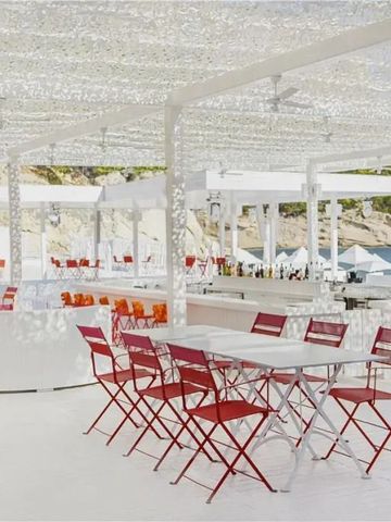 Stilvolle Strandbar mit roten und weißen Stühlen unter einem lichtdurchlässigen Dach