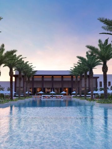 Großer Pool von Palmen umgeben mit Blick auf Hotelgebäude bei Sonnenuntergang