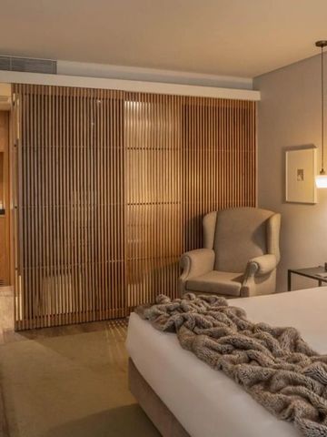 Komfortables Zimmer mit Holzelementen, Doppelbett und gemütlichem Sessel