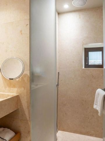 Marmor-Duschbereich mit Glasabtrennung und Regendusche